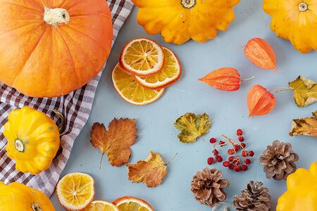 Bright autumn background. Top view of a white and brown checked kitchen towel, orange pumpkin,...