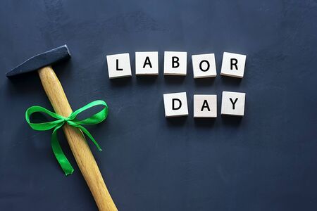 Labor day concept, hammer with a green bow on a black background. Copy space for text.の写真素材