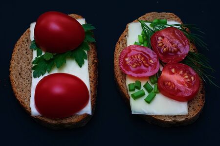 A variety of sandwiches with various fillings on a dark background. Sandwiches with sprats, with sardines on bread with herbs and sandwiches with tomatoes on a dark background. Food photography. Sandwich concept for breakfast or picnicの写真素材