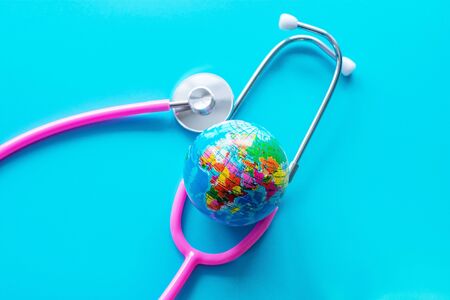 Stethoscope, pink, with a globe on a blue background. Save the world, global healthcare and green earth day conceptの写真素材