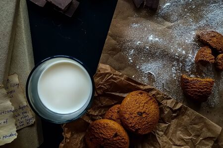 Broken cookies, nuts, chocolate, recipe books on a dark background.