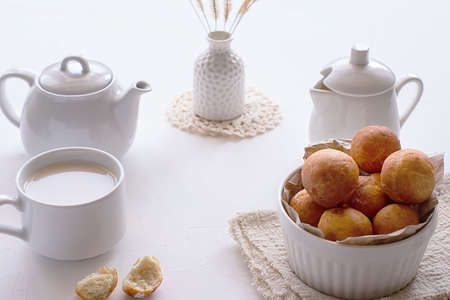 White teapot, a cup of tea and a bowl with donuts on a light background. Breakfast conceptの写真素材
