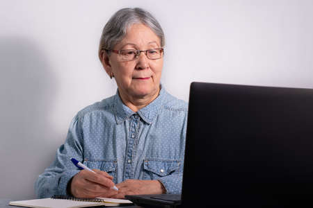 Senior business woman with laptop. Elderly woman working on laptop computer, smiling. Isolated over white backgroundの写真素材