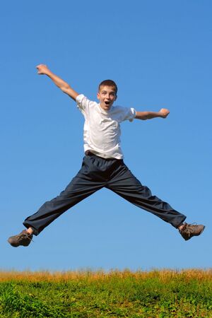 Happy and winning boy jumping on the blue sky backgroundの写真素材