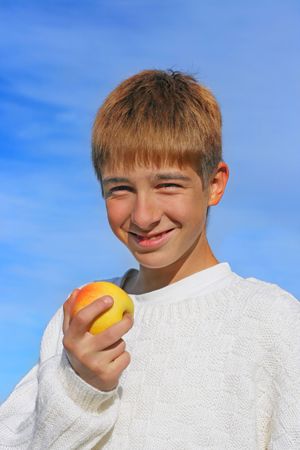 isolated on the blue sky teenage boy with the appleの写真素材