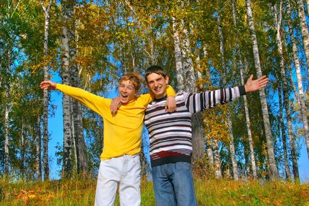 two smiling boys stand in autumn forestの写真素材