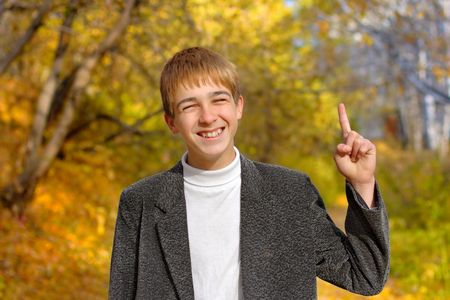 boy stand with finger up in autumn parkの写真素材
