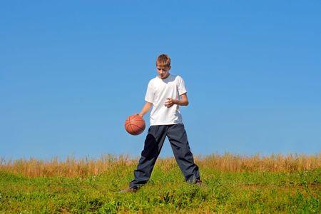 a boy dribbling a basketball in a gameの写真素材