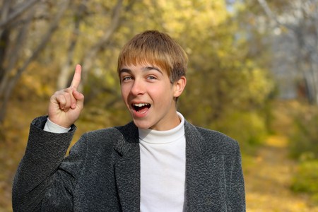 boy stand with finger up in autumn parkの写真素材