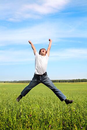 Happy teenager jumping on the meadowの写真素材