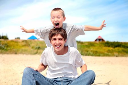 happy teenager and kid on the beachの写真素材