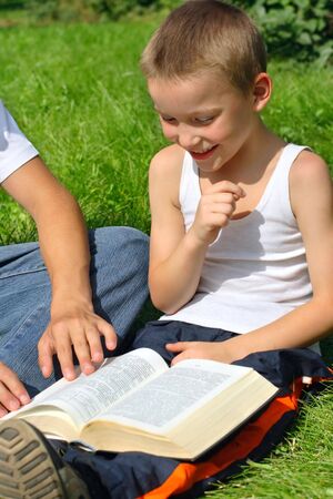 The happy kid with a book on a summer meadowの写真素材