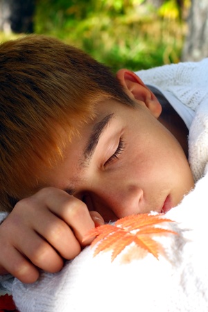 tired teenager sleeping in the autumn forestの写真素材