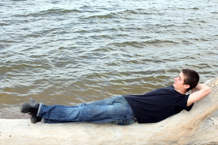 happy young man lying near the waterの写真素材
