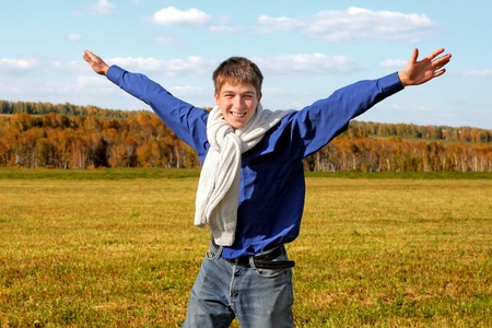happy teenager with hands up in the autumn fieldの写真素材