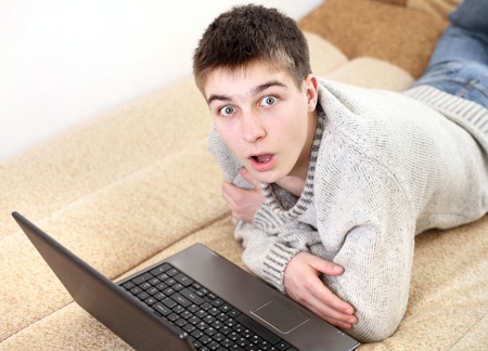 amazed young man with notebook on sofaの写真素材