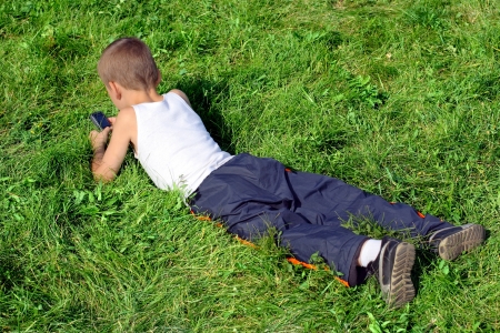 Little Boy with Mobile Gadget in the Summer Parkの写真素材