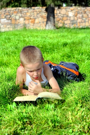 Serious Little Boy reads a Book in the Summer Parkの写真素材