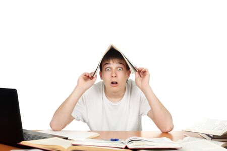 Surprised student at the school desk cover his head with exercise bookの写真素材