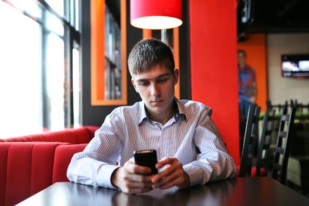 Sad Young Man with Mobile Phone at the tableの写真素材