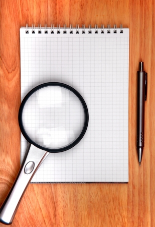 Blank Writing Pad and Pen and Loupe On The Brown Table Closeupの写真素材