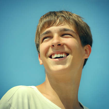 Toned photo of Cheerful Teenager Portrait on the blue sky backgroundの写真素材