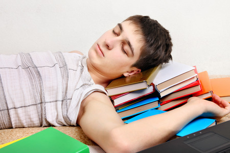 Tired Teenager sleeping on the Books at the Homeの写真素材