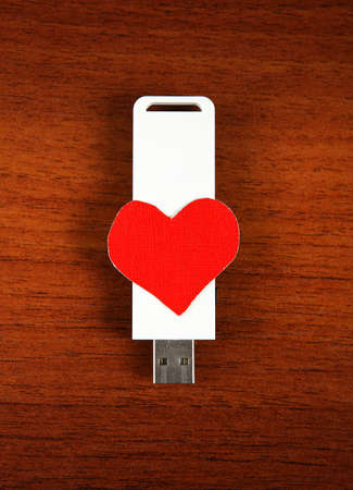 USB Flash Drive with Heart Shape on the Wooden Backgroundの写真素材