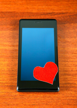Heart Shape and Cellphone on the Wooden Backgroundの写真素材