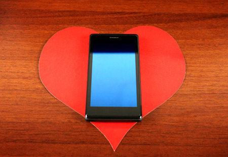Heart Shape and Cellphone on the Wooden Backgroundの写真素材