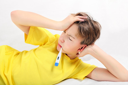 Sick Kid with Thermometer on the Bedの写真素材