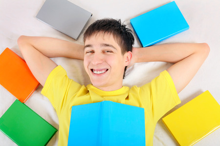 Happy Teenager with a Books on the Bedの写真素材