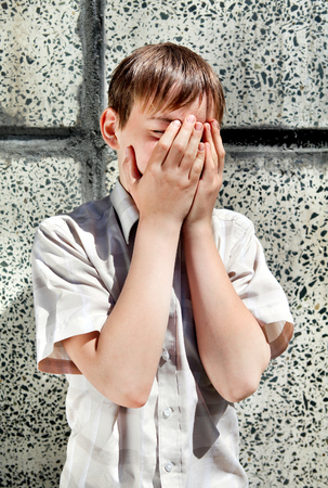 Sad and Troubled Kid by the Wall hide the Faceの写真素材