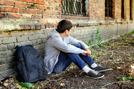 Sad Teenager near the Brick Wall of the Old Houseの写真素材