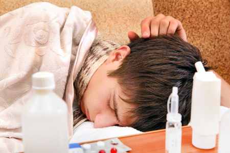 Sick Young Man sleep on the Sofa with Pills on foregroundの写真素材