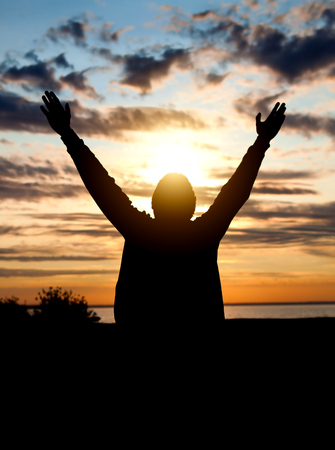 Happy Man Silhouette with Hands Up on the Sunset Background