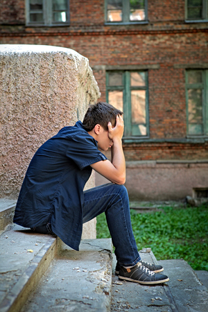 Sad and Stressed Teenager sit on the City Streetの写真素材