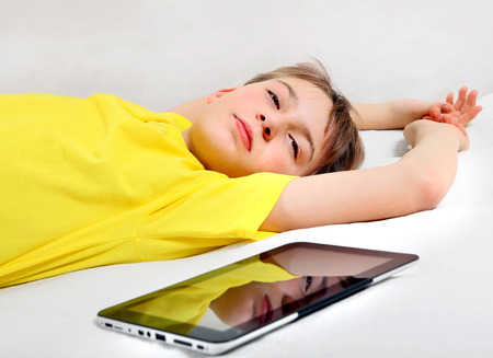 Tired Kid with Tablet Computer on the Bedの写真素材
