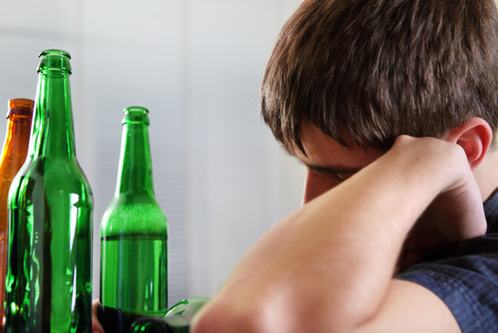Tired Young Man with Bottle of the Beer at the Homeの写真素材
