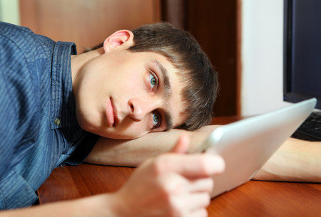 Tired Young Man with Tablet Computer at the Homeの写真素材