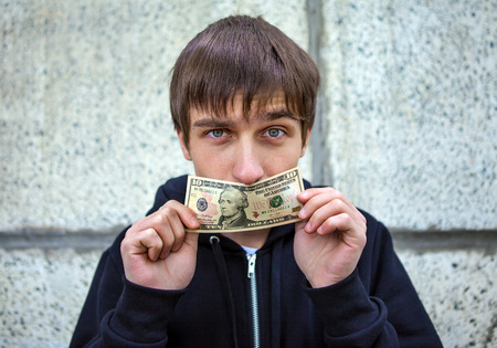 Young Man close the Mouth with American Dollars by the Wallの写真素材