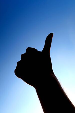 Hand Silhouette with Thumb Up on the Sky Background closeupの写真素材