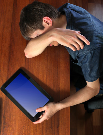Tired Young Man sleep with Tablet Computer on the Tableの写真素材