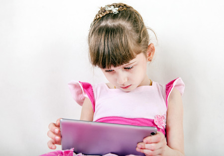 Little Girl with Tablet Computer on White Wall Backgroundの写真素材