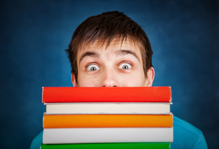 Surprised Student behind the Books on the Blue Backgroundの写真素材