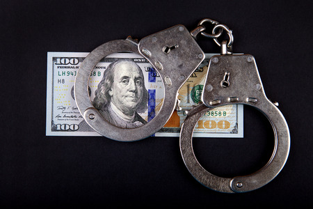 American Dollars and Handcuffs on the Black Background