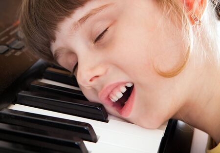 Tired Small Girl sleep on the Piano Keyboardの写真素材