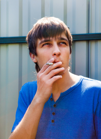 Young Man with Cigarette on the Wall Background outdoorの写真素材