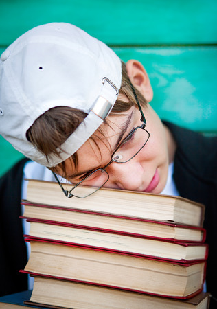 Sad Teenager with a Books by the Wooden Wall Backgroundの写真素材