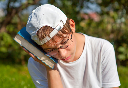 Sad Teenager with the Book in the Summer Parkの写真素材